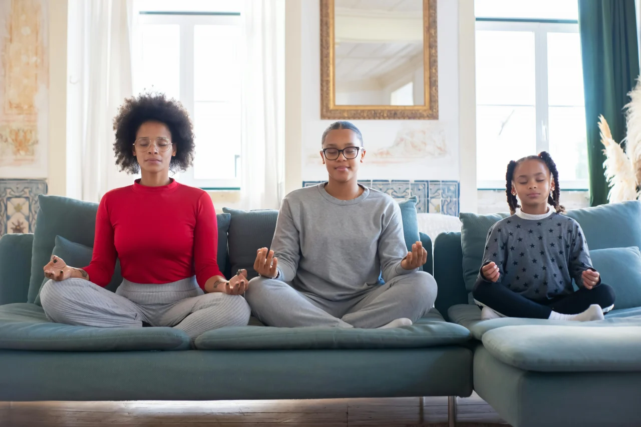 Meditationstechniken 3 drei Frauen meditieren gemeinsam mit unterschiedlichen Meditationstechniken auf dem Sofa