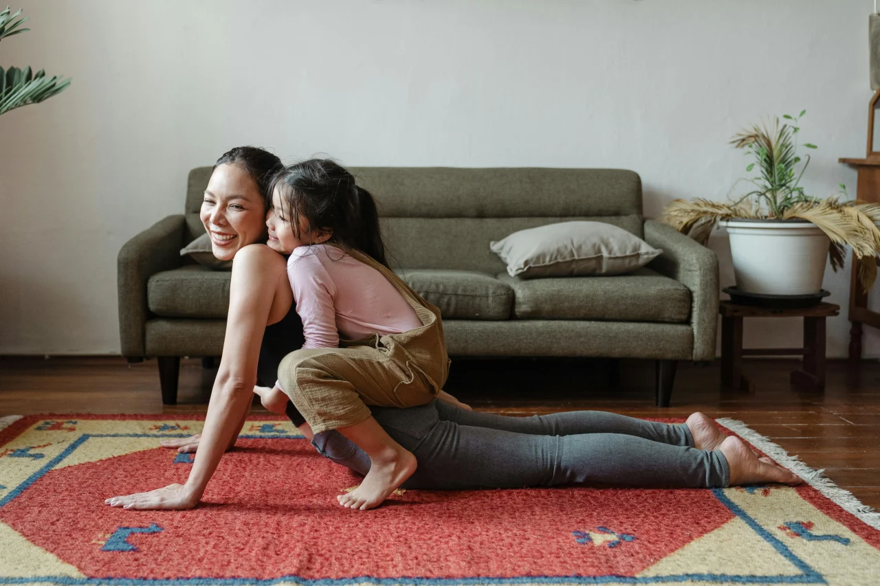 8 Tipps gegen Chronische Schmerzen 2 Tochter sitzt auf dem Rücken der Mutter in Yoga Pose