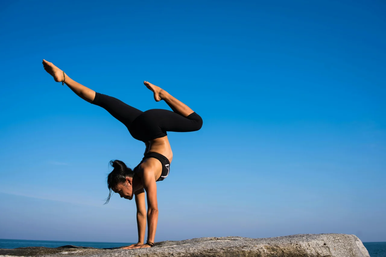 Yoga und Meditation 1 Frau in einer Yoga Pose im Handstand auf einer Klippe am Meer