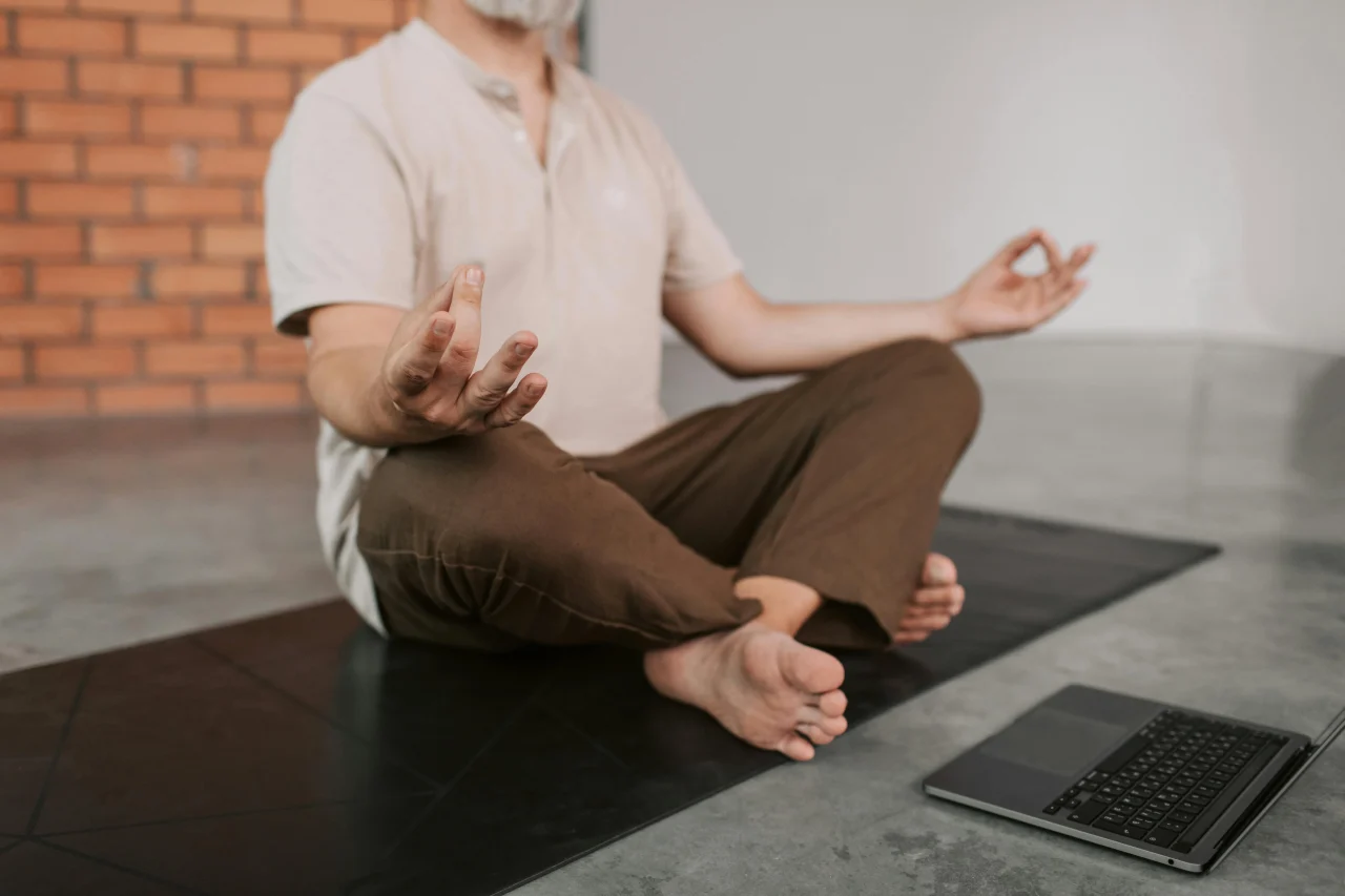 Meditation Rückenschmerzen 3 Mann meditiert auf dem Boden aufrecht im Schneidersitz vor einem Laptop