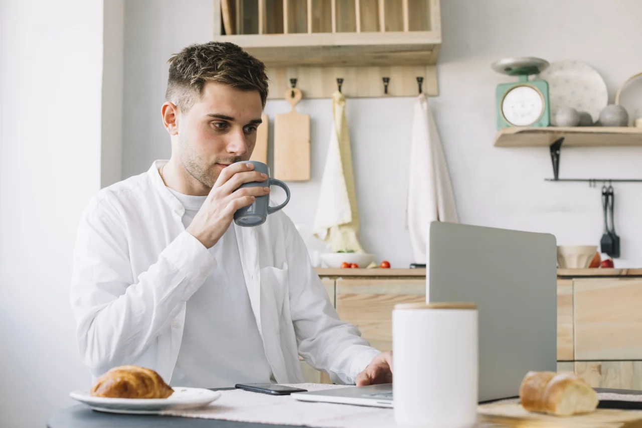 handsome man working laptop drinking coffee kitchen 1