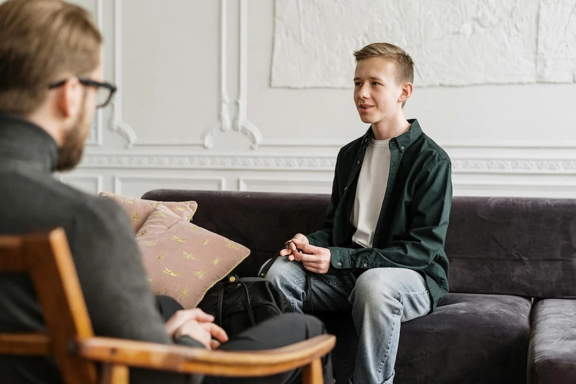 Zwangsstörung 2 Therapiegespräch Junge auf der Couch spricht mit Therapeuten auf dem Stuhl