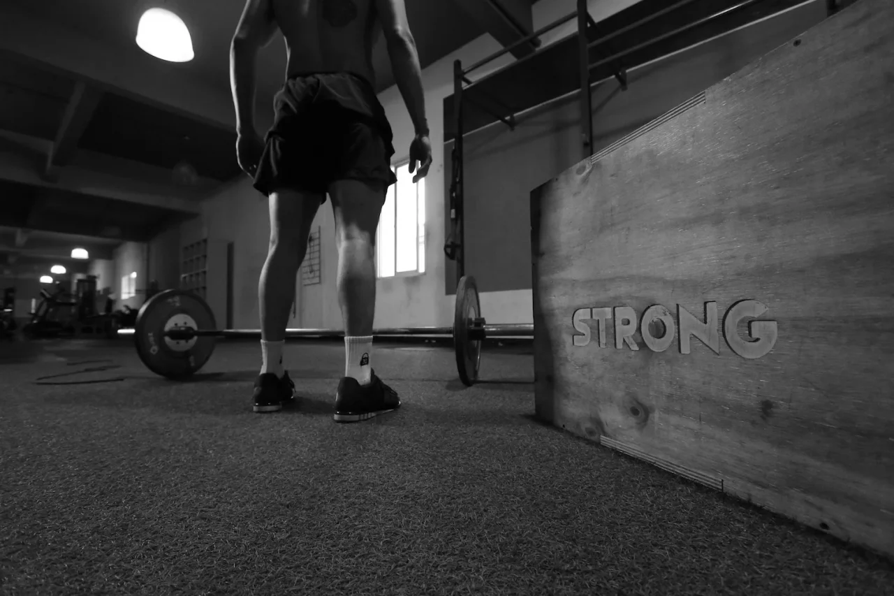 Resilienz stärken durch Training 1 Mann beim Training im Gym, Strong steht auf einer Box neben ihm