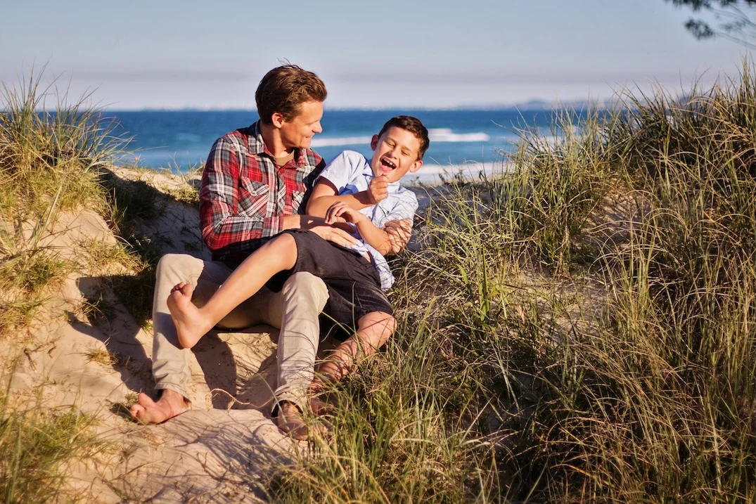 Meditieren mit Kindern: Warum es wichtig sein kann von klein auf das Meditieren zu lernen 3 Vater lacht gemeinsam mit Sohn am Strand